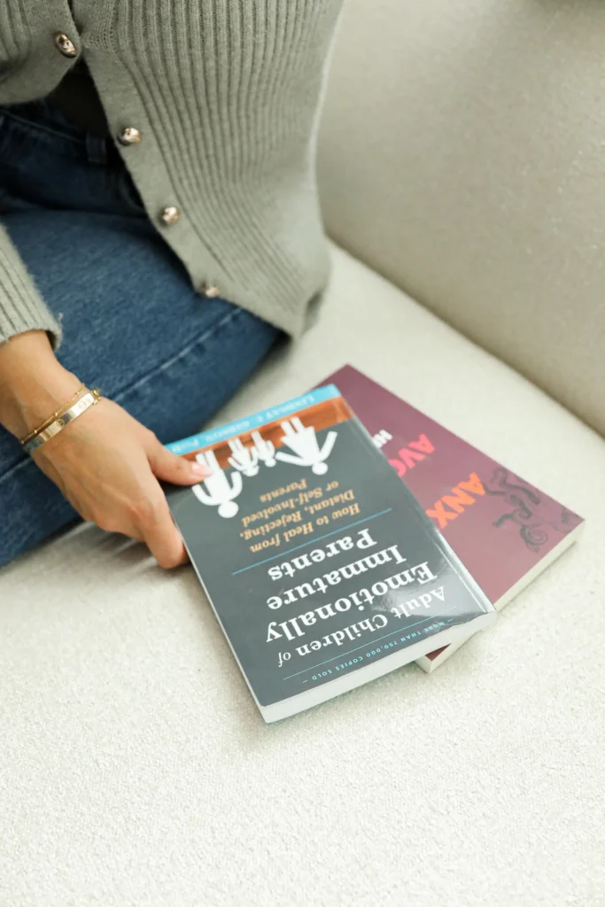 Close-up of Natasha Wahi holding a mental health book in a therapy setting, representing evidence-based counseling.