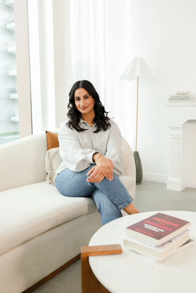 Natasha Wahi, sitting on a white couch, providing clinical supervision for LMHCA, LMFTA, and LICSW associates in Washington.