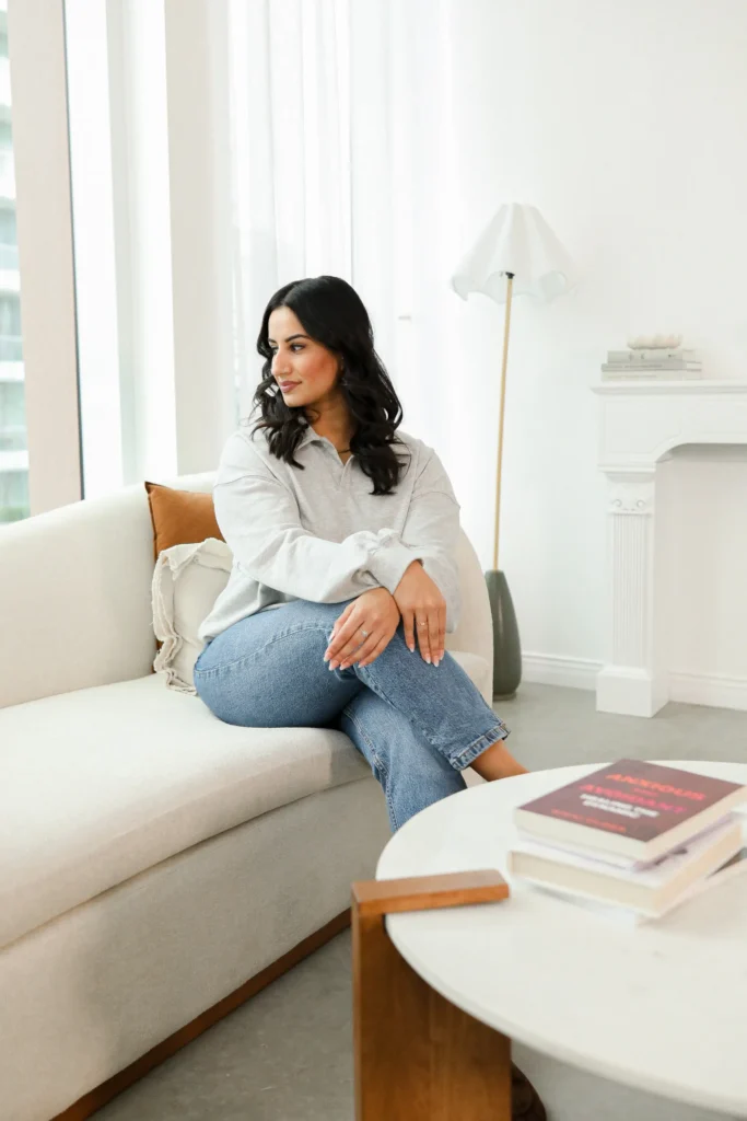 Natasha Wahi sitting thoughtfully in a serene therapy room designed for mental health counseling.